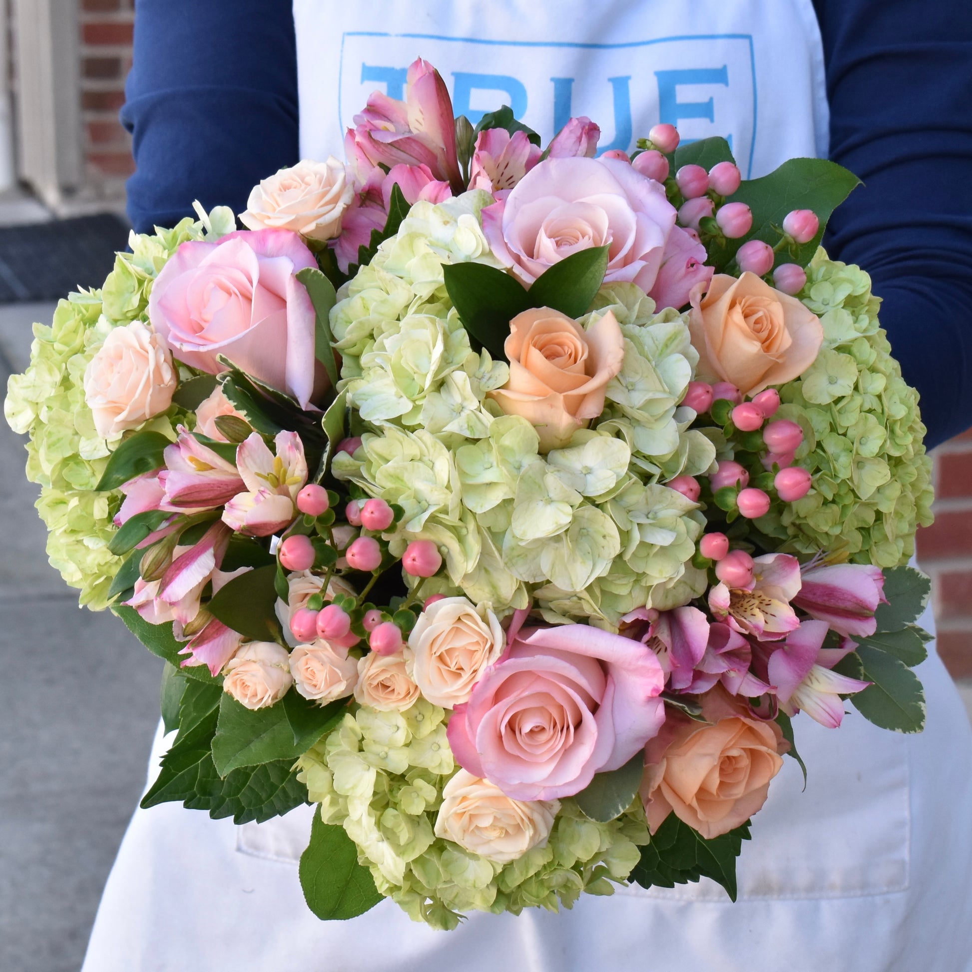 Soft green hydrangea with peach and soft pink flowers arranged in a bouquet