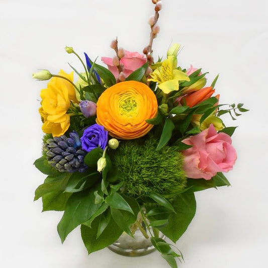 Bright spring flowers arranged in a low glass table centrepiece