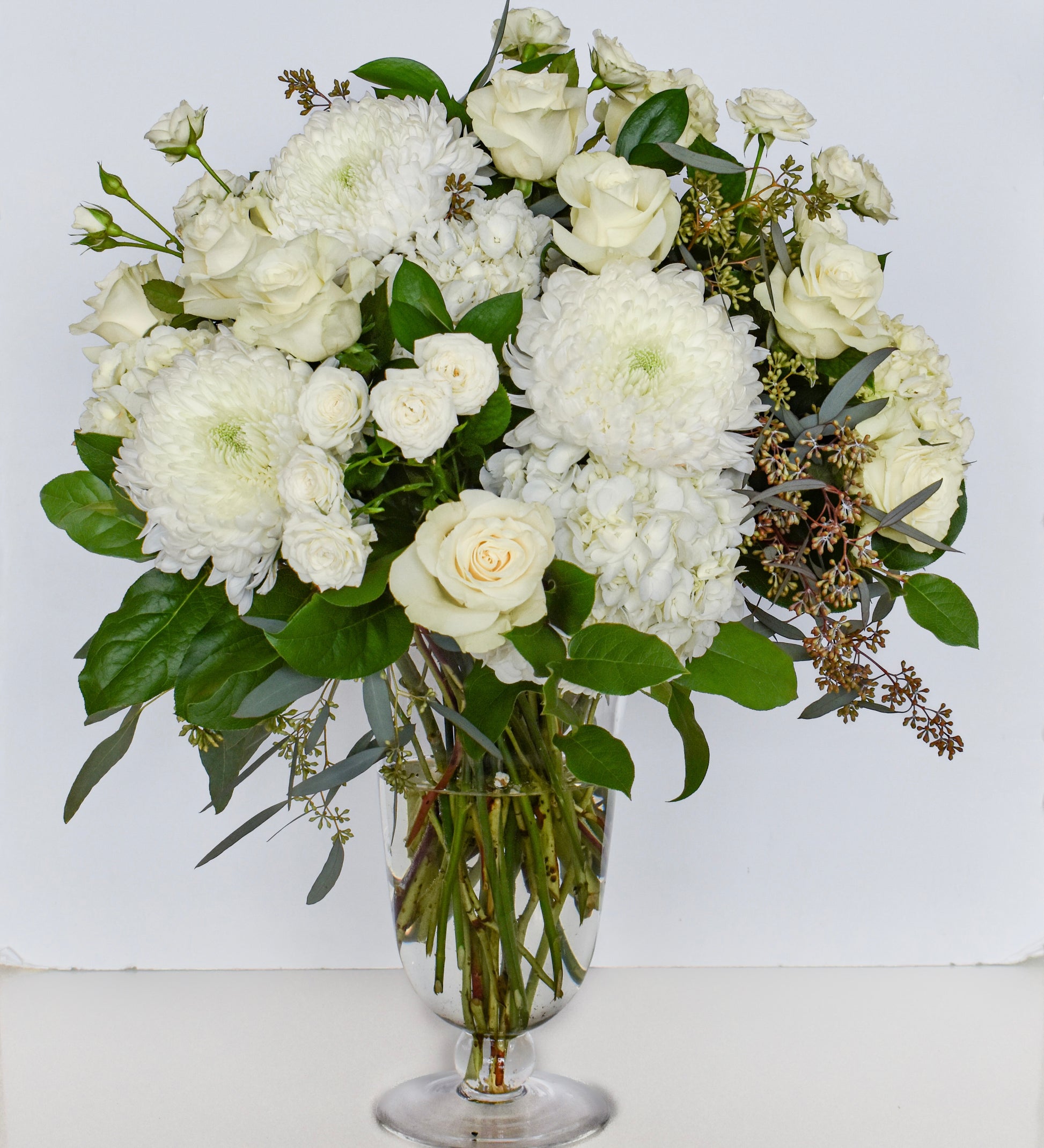 White flowers arranged in a tall glass footed vase