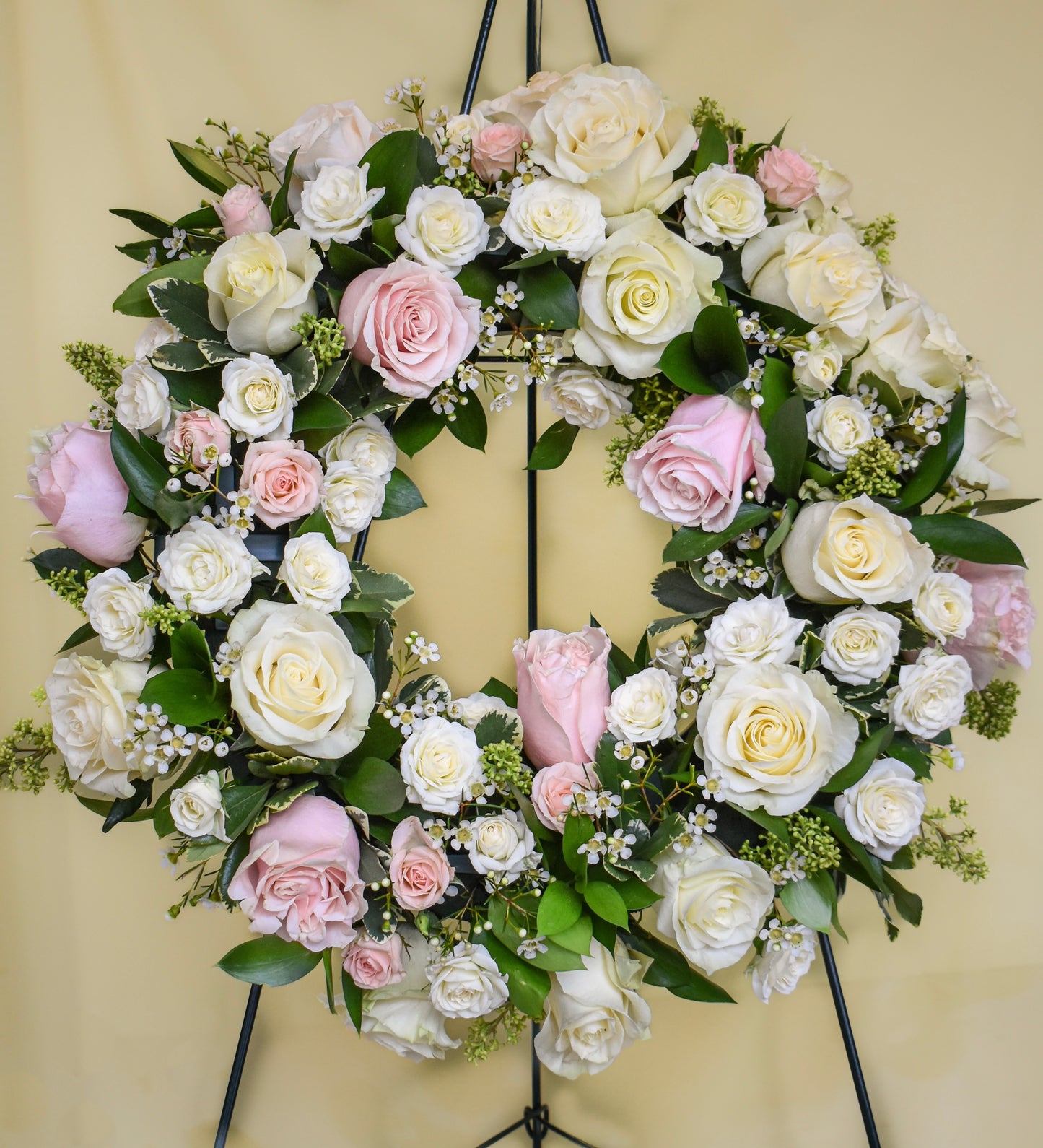 White and light pink roses and spray roses arranged in a sympathy wreath