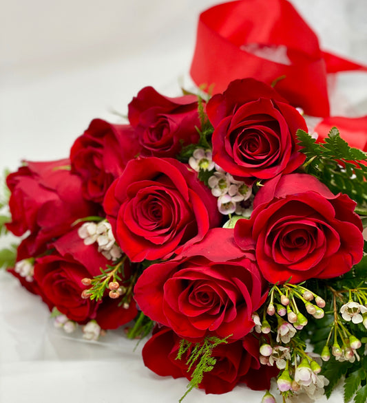 Red roses with white wax flower and greens in a bouquet