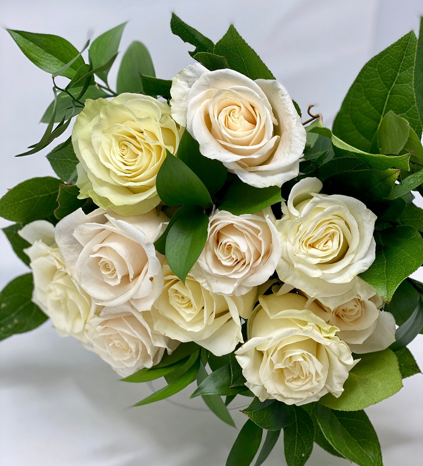 White roses arranged in a bouquet with greens