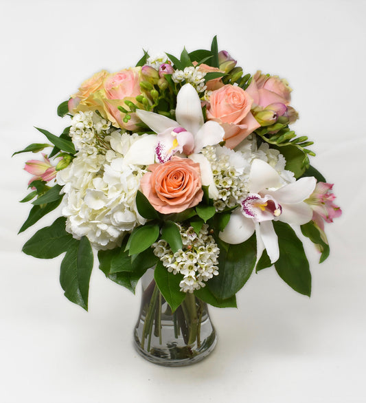 Light pink and peach flowers designed with white hydrangea in a tall vase
